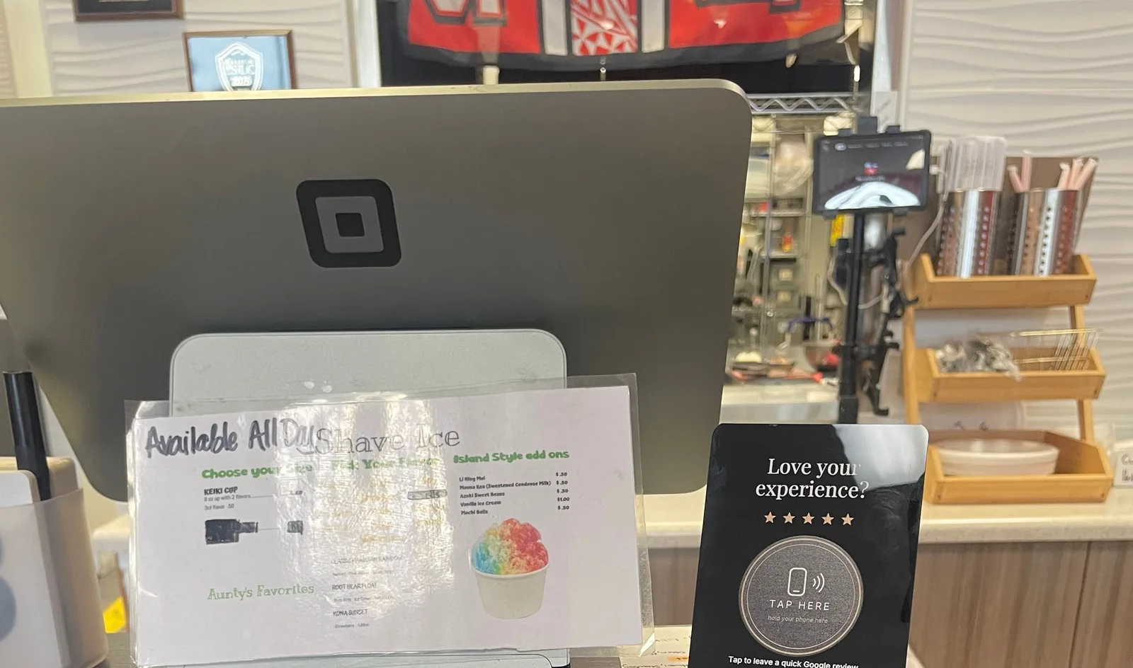 A black Dime Media tap stand on the service counter at Aunty's Hawaiian Kitchen, next to the card reader and the menu.